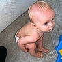 toddler, child, diaper, carpet, floor, crouching, blue_eyes, toy, plastic_toy, curious, indoor, home, person, furniture, couch, blond_hair, skin, barefoot, playing, baby