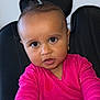 toddler, child, baby, pink_clothing, face, portrait, chair, curly_hair, earrings, indoor, skin, hands, looking_at_camera, young_child, sitting, expression, casual_clothing, person, cute, small_pony_tail