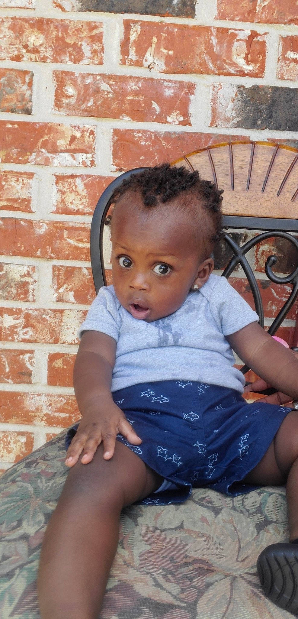 De'Angelo is registered to the contest to win money with this photo: baby, black_hair, cheek, child, ear, eye, face, forehead, head, leg, neck, person, sitting, smile, surprise, toddler