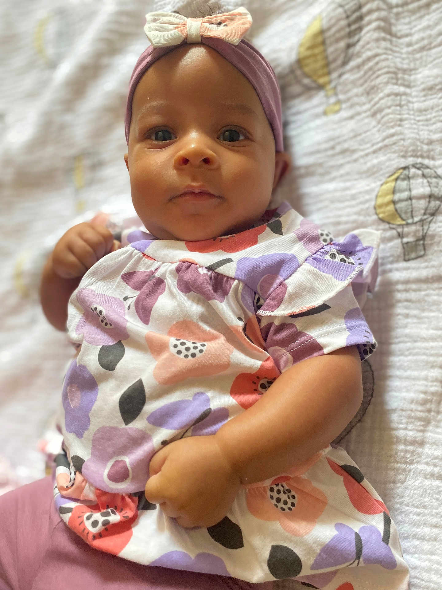Hanaé a rejoint le concours — aidez-le/la à gagner de superbes lots ! baby, infant, child, headband, bow, dress, floral_pattern, blanket, hot_air_balloon, cute, portrait, lying_down, soft_texture, colorful, clothing, person, young_child, indoors, closeup, adorable