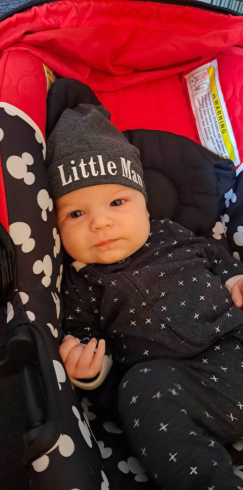 William is registered to the contest to win money with this photo: baby, baby_products, baby_toddler_clothing, beanie, cap, cheek, child, comfort, fashion_accessory, gesture, headgear, headwear, knit_cap, outerwear, pattern, person, sitting, sleeve, thumb, toddler