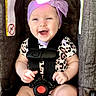 baby, child, infant, smiling, happy, portrait, car_seat, harness, headband, bow, purple, leopard_print, outdoor, vehicle, safety, seated, face, hands, bright, photography