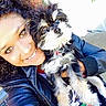 black_and_white_dog, brick_wall, close_up, collar, curly_hair, dog, dog_tag, eyes, fur, hand, happy, leather_jacket, outdoor, person, pet, porch, selfie, small_dog, smile, sunlight