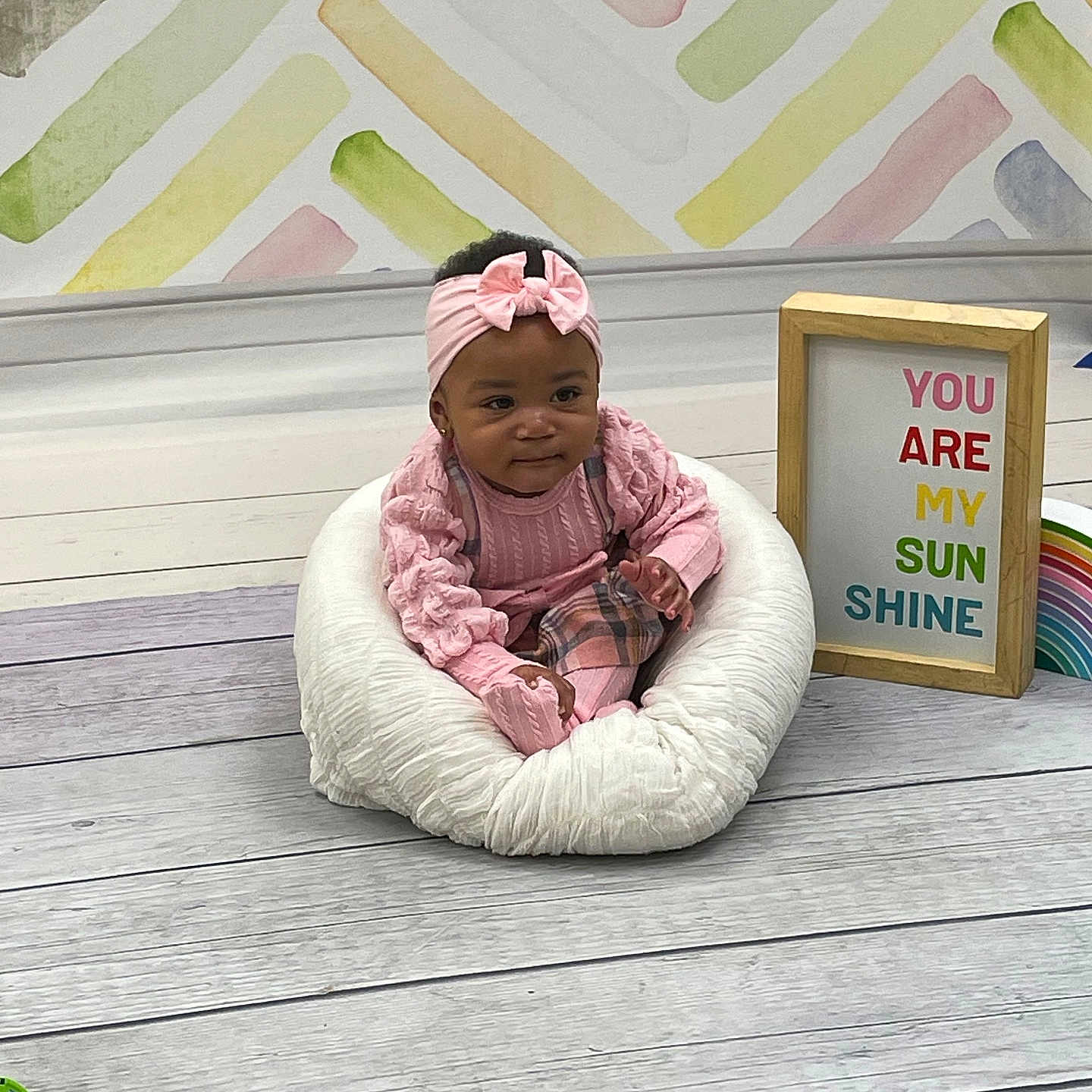 Miyori joined the competition — help win amazing prizes! baby, child, colorful_wall, cushion, cute, decor, floor, frame, headband, indoor, infant, pink_clothing, portrait, rainbow, sign, sitting, smiling, text, wall, wooden_floor