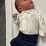Jaxxon-Brian joined the competition — help win amazing prizes! baby, infant, onesie, clothing, booties, pom_poms, changing_mat, carpet, floor, person, newborn, cute, lying_down, blue, white, navy, knitted, warm, soft, curious
