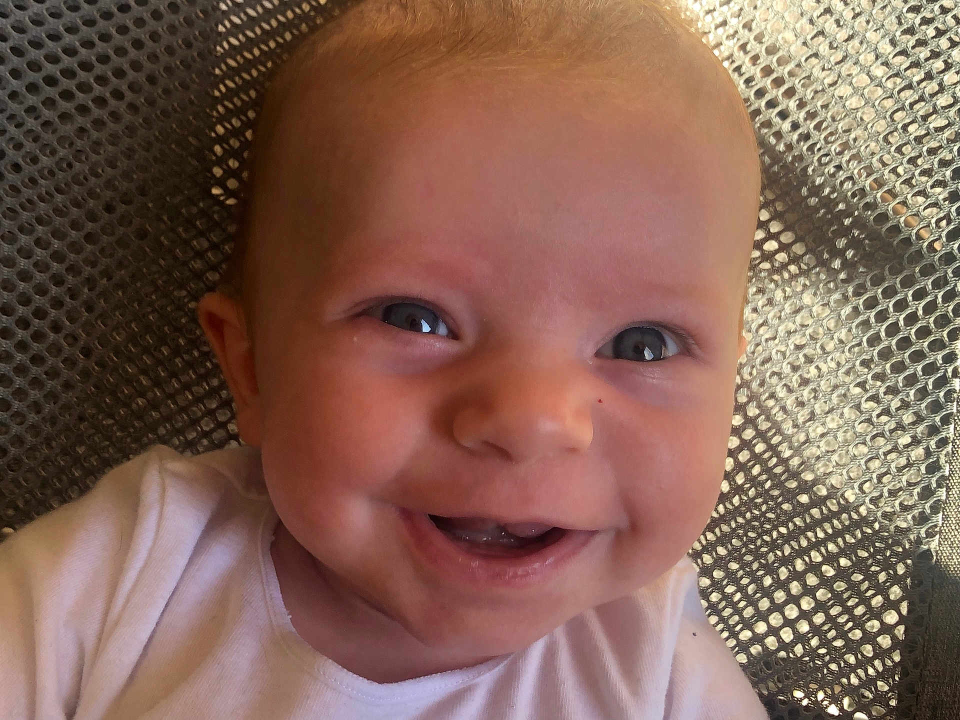 Hunter is registered to the contest to win money with this photo: baby, smiling, face, close_up, white_shirt, happy, child, infant, skin, eyes, mouth, teeth, texture, background, mesh, pattern, portrait, cute, person, young
