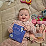 Stella a rejoint le concours — aidez-le/la à gagner de superbes lots ! baby, infant, polka_dot, onesie, book, toy, rattle, blanket, quilt, soft_toy, smiling, child, indoors, cute, playful, lying_down, hand, face, person, cozy