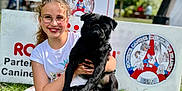 Saint Maxime participe au concours pour gagner de l'argent avec cette photo : girl, dog, pug, black_dog, glasses, smile, holding, pet_show, royal_canin, signage, outdoor, grass, portrait, happy, sitting, collar, festival, trees, youth, photography