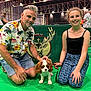 Harry a rejoint le concours — aidez-le/la à gagner de superbes lots ! dog, puppy, person, man, girl, smiling, leash, indoor, event, exhibition, green_floor, floral_shirt, glasses, kneeling, arena, banner, logo, pet_show, cute, family