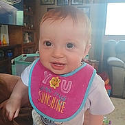 Isabelle joined the competition — help win amazing prizes! baby, child, smile, bib, indoor, living_room, television, furniture, window, person, clothing, face, hair, eyes, hand, toy, carpet, portrait, happy, cute