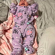 Ailany is registered to the contest to win money with this photo: baby, infant, crying, sleeping, onesie, purple_clothing, patterned_clothing, blanket, bed, bedding, pink_blanket, white_blanket, stuffed_toy, portrait, indoors, cozy, lying_down, raised_arms, fuzzy_texture, close_up