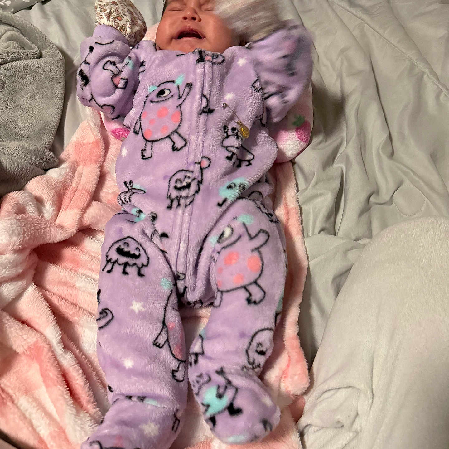 Ailany is registered to the contest to win money with this photo: baby, infant, crying, sleeping, onesie, purple_clothing, patterned_clothing, blanket, bed, bedding, pink_blanket, white_blanket, stuffed_toy, portrait, indoors, cozy, lying_down, raised_arms, fuzzy_texture, close_up