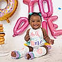 baby, child, smiling, curly_hair, balloons, donuts, birthday, celebration, colorful, sitting, outfit, drool, cute, decorations, happy, legs, feet, white_background, party, girl