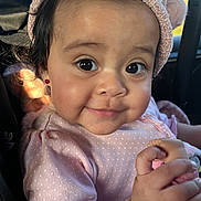 Diana joined the competition — help win amazing prizes! baby, child, infant, face, smile, pink_clothing, hat, earrings, doll, hand, car_seat, seatbelt, natural_light, portrait, cute, young_child, indoor, person, cozy, happy