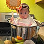 baby, infant, kitchen, pot, vegetables, carrot, corn, potato, celery, wooden_spatula, headband, bow, stove, countertop, sign, five_months, prayer_plaque, green_wall, cute, child