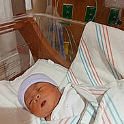 Kennedi is registered to the contest to win money with this photo: newborn, baby, hospital, bassinet, blanket, hat, medical_equipment, sleeping, infant, bed, healthcare, patient, nursery, person, wrapped, cozy, cute, indoor, quiet, resting