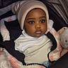 baby, child, infant, beanie, jacket, plush_toy, stroller, white_shirt, cozy, cute, warm_clothing, fur_texture, portrait, wide_eyes, indoor, black_hair, soft_toy, person, young_child, expression