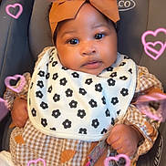 Keilani is registered to the contest to win money with this photo: baby, child, car_seat, headband, bow, bib, pacifier, clothing, patterned_bib, patterned_clothing, pink_hearts, infant, cute, portrait, indoor, person, sitting, closeup, adorable, soft_light