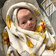 Leona is registered to the contest to win money with this photo: baby, blanket, infant, face, wrapped, cushion, seat, warning_label, soft_texture, indoors, cute, child, newborn, closeup, expression, warm, comfort, person, portrait, fabric