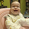 Roselynn is registered to the contest to win money with this photo: baby, high_chair, smiling, indoor, bib, onesie, food_stains, face, hand, furniture, toy, shelf, cat_tree, door, room, child, person, happy, portrait, expression
