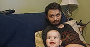 Roselynn is registered to the contest to win money with this photo: adult, baby, beard, casual, child, clothing, couch, furniture, happy, home, indoor, lamp, living_room, man, person, pillow, portrait, relaxing, seated, smile