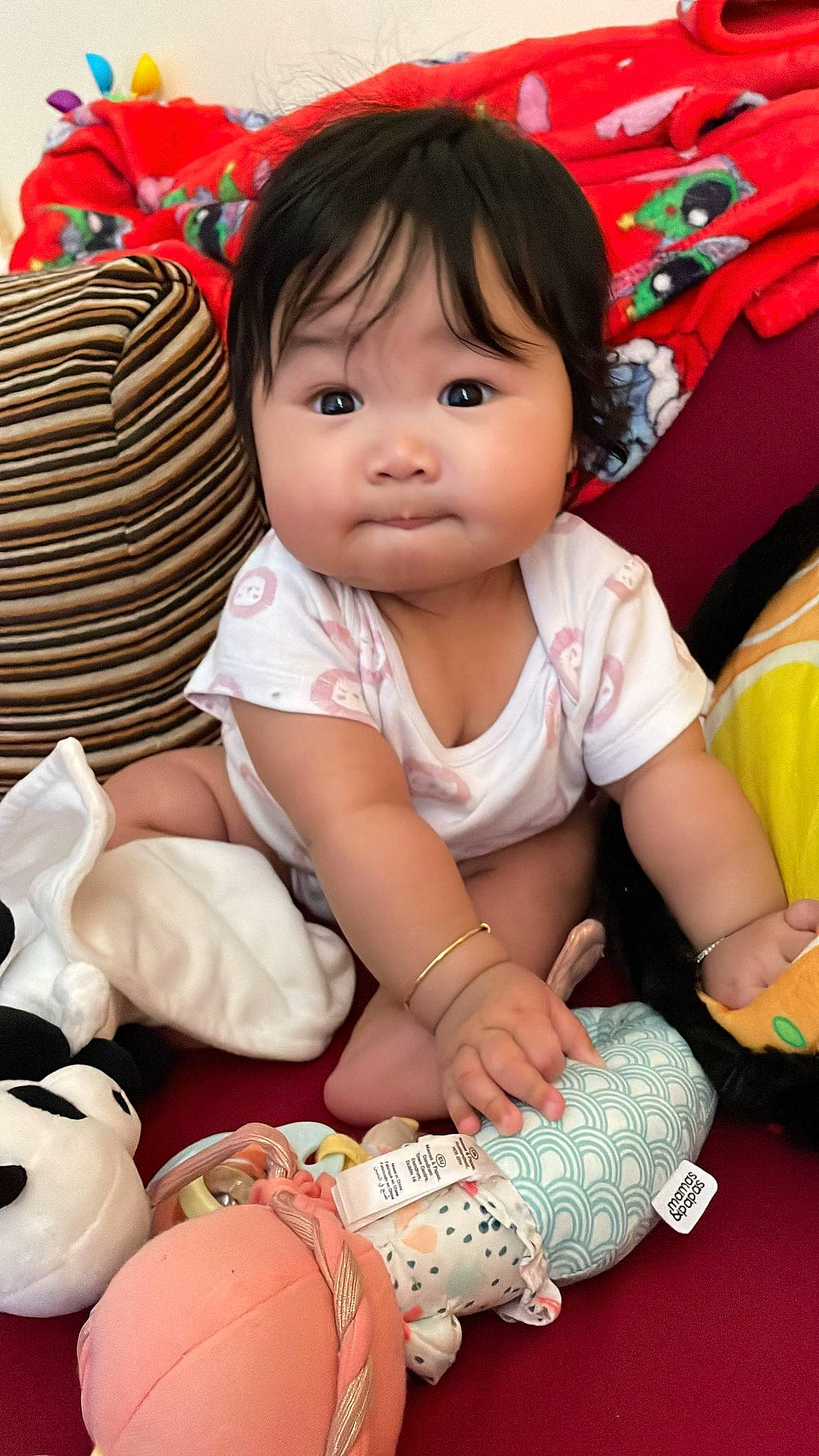 Sky is registered to the contest to win money with this photo: arm, baby, baby_toddler_clothing, black_hair, cheek, child, eye, facial_expression, finger, fun, hand, happy, iris, person, pink, red, sitting, skin, sleeve, thigh