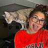 Nyx joined the competition — help win amazing prizes! woman, cat, glasses, tongue_out, selfie, indoor, casual_clothing, orange_sweatshirt, pet, shoulder, playful, curious, brown_hair, updo_hairstyle, room, wall_art, couch, decor, eyewear, young_adult
