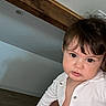 baby, child, toddler, face, person, indoor, white_clothing, wooden_beam, curious_expression, buttoned_shirt, skin, head, hair, holding, wall, floor, portrait, casual, young, looking