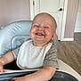 toddler, child, smiling, high_chair, bib, messy, food, face, happy, indoor, wood_floor, door, short_sleeve_shirt, carhartt, baby, hands, sitting, cheerful, light, home