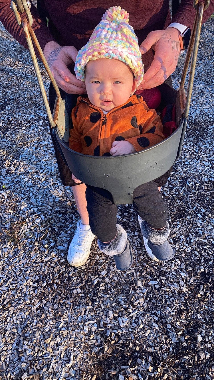 Leilani is registered to the contest to win money with this photo: baby, baby_carriage, baby_products, baby_toddler_clothing, blue, child, comfort, eye, grass, happy, head, headwear, leisure, people_in_nature, person, recreation, sitting, sneakers, soil, swing