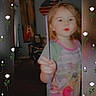 Alicia is registered to the contest to win money with this photo: child, blurry, indoor, person, holding, stick, red_lips, wall_decor, painting, flag, furniture, room, young_child, pattern, floral_border, white_roses, decorative, portrait, playful, casual