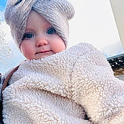 Louise a rejoint le concours — aidez-le/la à gagner de superbes lots ! baby, child, face, blue_eyes, knit_hat, bow, fluffy_jacket, winter_clothing, outdoor, sky, portrait, cute, warm_clothing, infant, headwear, soft_texture, smile, person, close_up, daylight