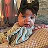 baby, infant, child, portrait, close_up, smiling, wide_eyed, bow, headband, blanket, cushion, bracelet, beads, personalized, indoors, cozy, home, seated, face, photography
