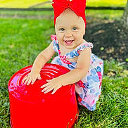 Addison joined the competition — help win amazing prizes! toddler, child, red_bow, floral_dress, grass, outdoor, bucket, toy, happy, smiling, playing, sunny, nature, greenery, baby, cute, hands, headband, summer, portrait