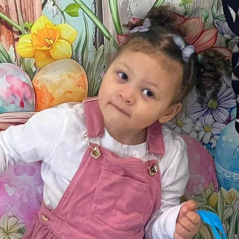 Leriah is registered to the contest to win money with this photo: child, girl, pink_pinafore, white_shirt, blue_bag, flowers, easter_eggs, mural, hair_bows, curly_hair, playful, portrait, indoors, colorful, decor, cute, young_child, smiling, standing, holiday_theme