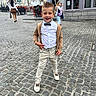 child, boy, smile, street, cobblestone, bow_tie, hoodie, pants, sneakers, urban, outdoor, person, fashion, confident, pose, daylight, city, sidewalk, people, background