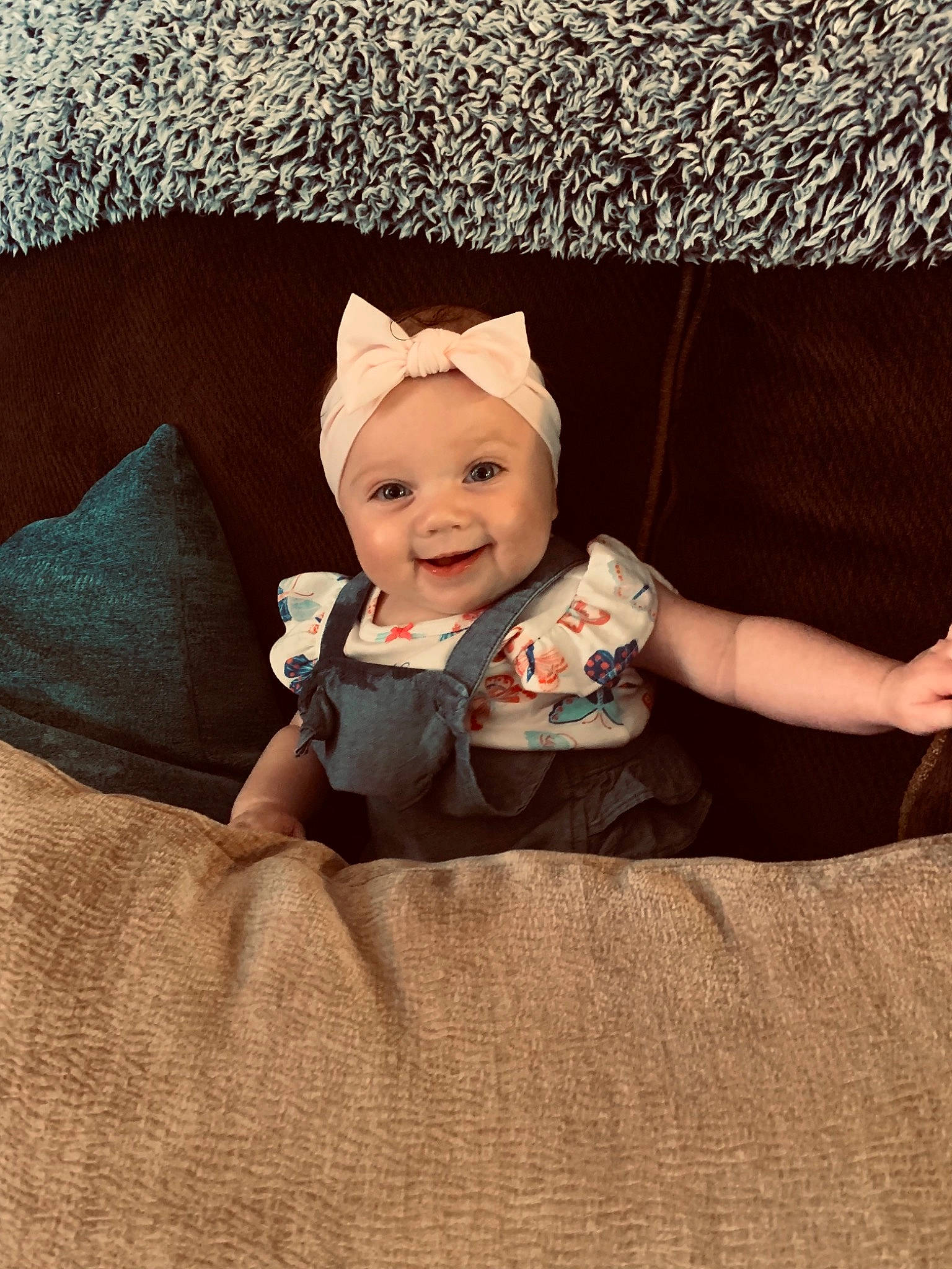 Addison is registered to the contest to win money with this photo: baby, baby_products, baby_toddler_clothing, beanie, child, comfort, eye, fashion_accessory, floor, flooring, happy, headwear, human_body, joy, linens, pattern, person, room, sitting, sleeve