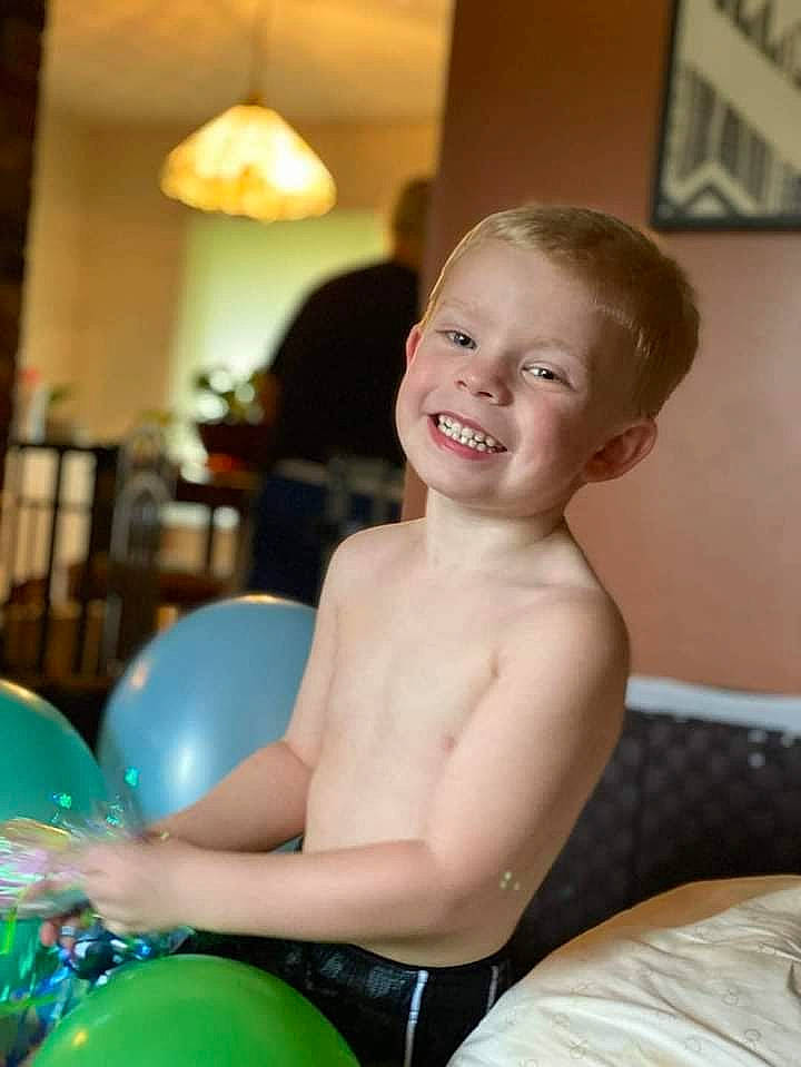 Kayden is registered to the contest to win money with this photo: abdomen, balloon, chair, chest, child, eye, fun, green, hairstyle, happy, head, human_leg, joy, knee, leg, leisure, party_supply, person, smile, thigh