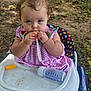 Willow joined the competition — help win amazing prizes! baby, child, high_chair, outdoor, grass, dirt, food, fork, plastic, bottle, cheese_puff, pink_dress, curly_hair, blue_eyes, polka_dot, sitting, messy, cute, portrait, nature