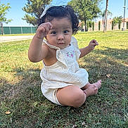 Amelia Guerrero is registered to the contest to win money with this photo: toddler, child, grass, outdoor, park, sunny, curly_hair, white_dress, baby, nature, greenery, trees, sitting, cute, person, young_child, daylight, playful, expression, barefoot