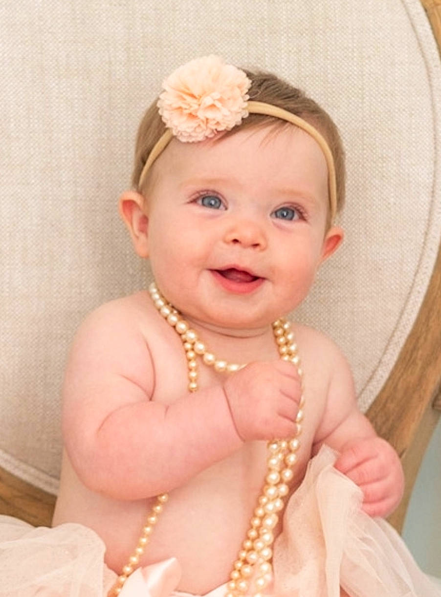 Skylar is registered to the contest to win money with this photo: baby, baby_toddler_clothing, body_jewelry, cheek, dress, ear, eye, hairstyle, happy, head, headgear, headpiece, human_body, iris, jewellery, joy, neck, person, pink, skin