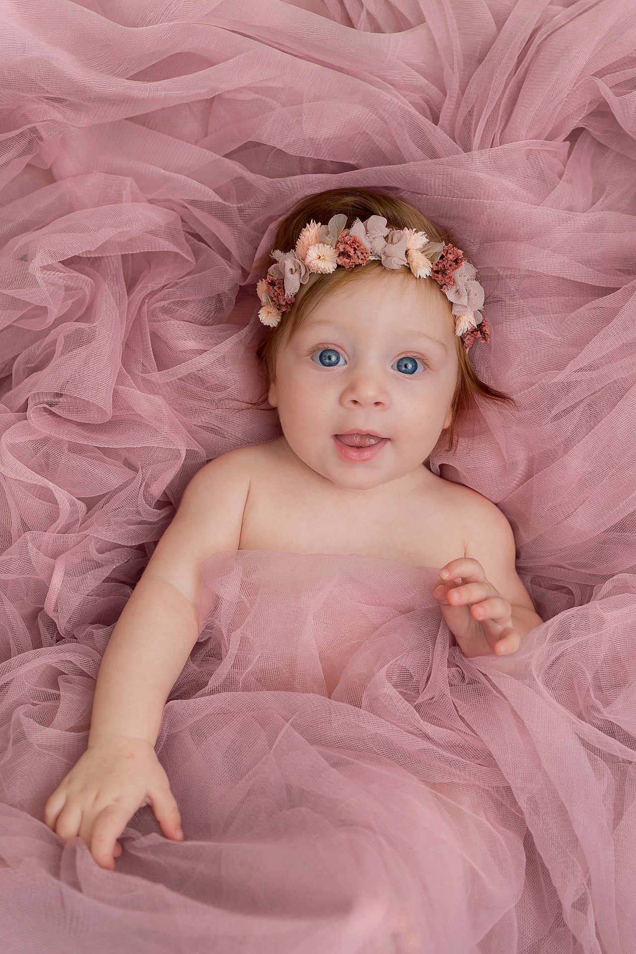 Elsa participe au concours pour gagner de l'argent avec cette photo : baby, infant, child, pink_tulle, flower_headband, blue_eyes, portrait, cute, soft_fabric, smiling, happy, skin, hand, face, lying_down, newborn, innocent, adorable, gentle_light, closeup