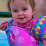 toddler, child, swimwear, floatation_device, smile, outdoor, pool, water, blue_sky, clouds, hand, person, building, pink_clothing, mermaid, seashell, colorful, happy, summer, play