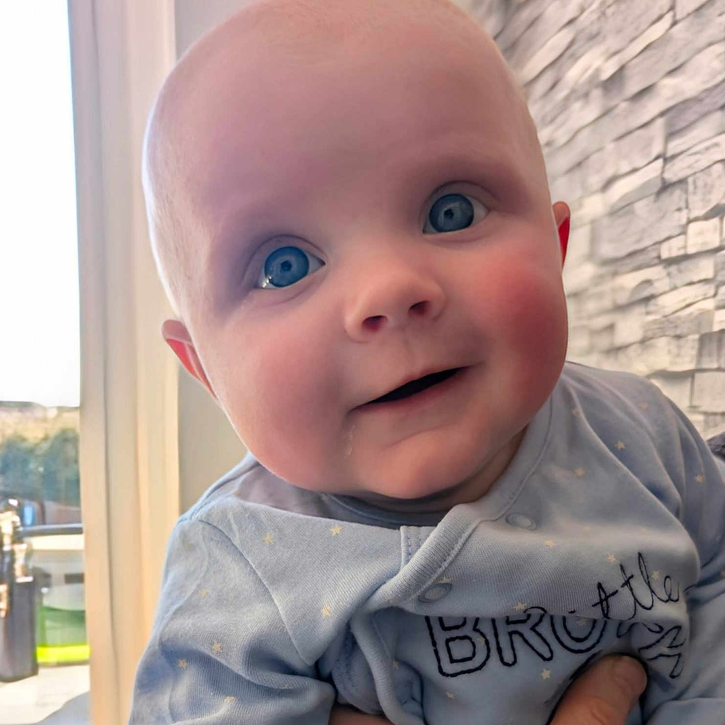Bodi is registered to the contest to win money with this photo: architecture, baby, building, clothing, door, dress, face, happy, head, newborn, pants, person, photography, portrait, shirt, sitting, smile, t_shirt, wall, window