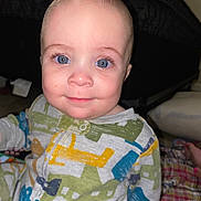 Jesse is registered to the contest to win money with this photo: baby, child, blue_eyes, smile, pajamas, airplane_pattern, indoor, face, person, infant, cute, happy, sitting, closeup, head, skin, expression, young, portrait, cozy
