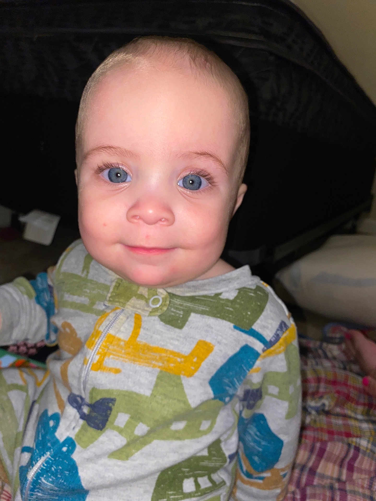 Jesse is registered to the contest to win money with this photo: baby, child, blue_eyes, smile, pajamas, airplane_pattern, indoor, face, person, infant, cute, happy, sitting, closeup, head, skin, expression, young, portrait, cozy