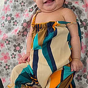 Mia is registered to the contest to win money with this photo: baby, child, smiling, headband, bow, colorful_clothing, striped_outfit, white_socks, blanket, floral_pattern, cute, happy, indoors, portrait, infant, person, lying_down, soft_texture, skin, playful