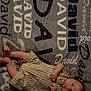 David is registered to the contest to win money with this photo: baby, bed, blanket, child, clothing, cute, fabric, foot, hand, indoors, infant, lying_down, name, pattern, person, portrait, skin, striped, text, young