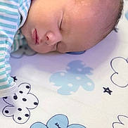 Matthew is registered to the contest to win money with this photo: baby, sleeping, striped_clothing, blanket, cartoon_clouds, infant, peaceful, cute, face, head, soft_lighting, indoors, child, newborn, portrait, resting, cozy, pattern, babywear, closeup