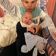 Ayden Harrault participe au concours pour gagner de l'argent avec cette photo : baby, blanket, boy, brother, child, clothing, couch, cozy, eyes, face, hands, holding, home_interior, patterned_fabric, pillow, plush_toy, portrait, seated, sibling, smile